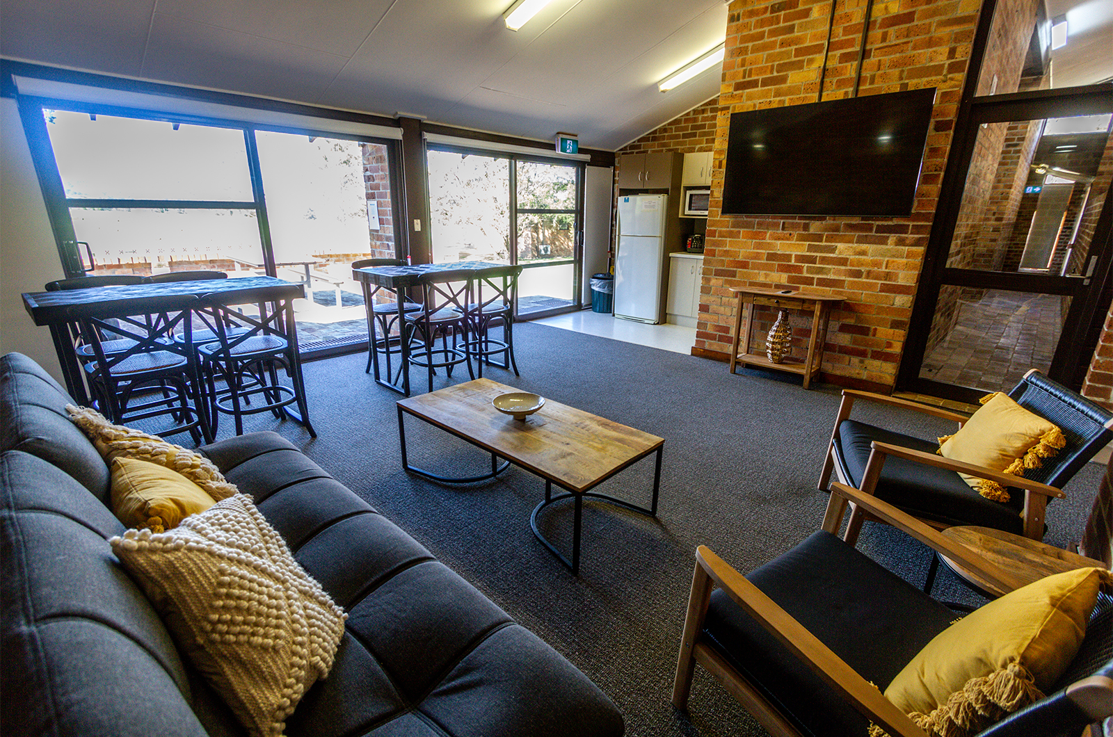 Tocal Glendarra common room with TV, couch, chairs and tables.