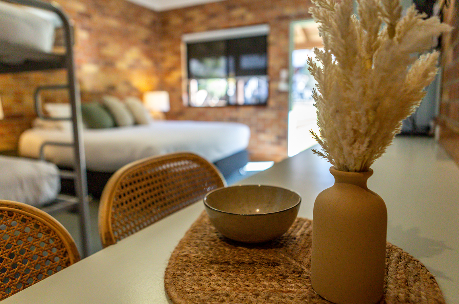 Tocal Glendarra bedroom with queen bed and bunks, focus on foreground vase of dried flowers