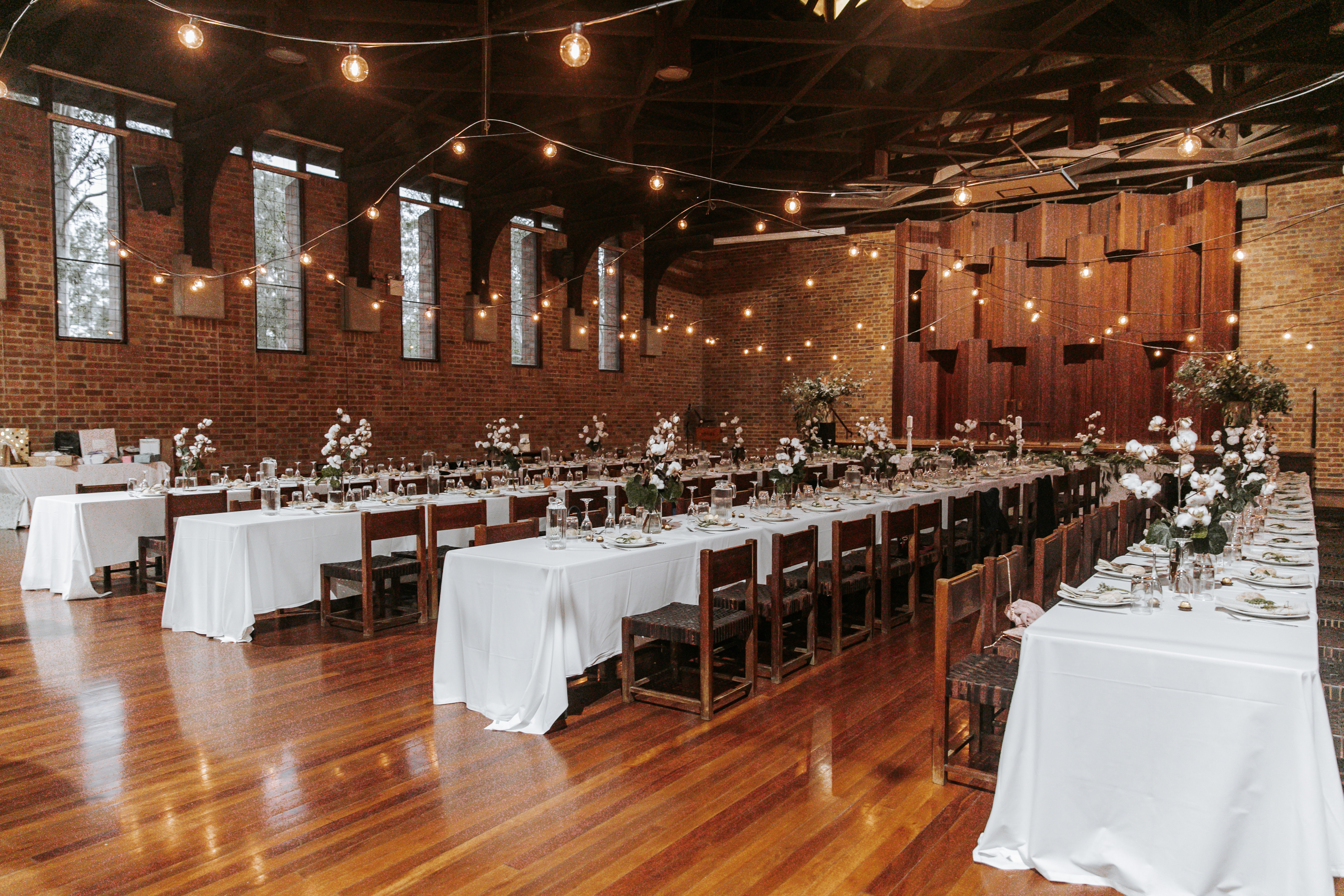 Long tables and chairs with formal settings, light garlands, flowers